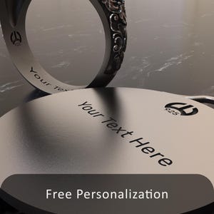 Pode incluir: Um anel de prata com um design intrincado. O anel &eacute; gravado com o texto "Your Text Here" e o n&uacute;mero "925". O anel est&aacute; sobre uma superf&iacute;cie prateada com o texto "Personaliza&ccedil;&atilde;o gratuita".