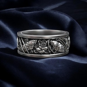 May include: A silver ring with a detailed design of two koi fish swimming around a lotus flower.