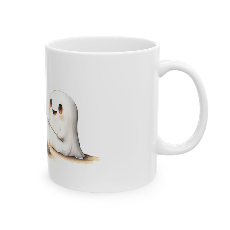 Puede incluir: Taza de caf&eacute; de cer&aacute;mica blanca con una ilustraci&oacute;n de dibujos animados de dos fantasmas amigables tom&aacute;ndose de la mano. Los fantasmas son blancos con ojos negros y sonrisas.