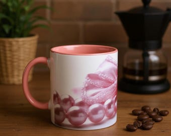 Op de afbeelding: Een witte keramische mok met een roze binnenkant en handvat. De mok heeft een ontwerp van roze parels en een roze strik. De mok staat op een houten oppervlak met koffiebonen.