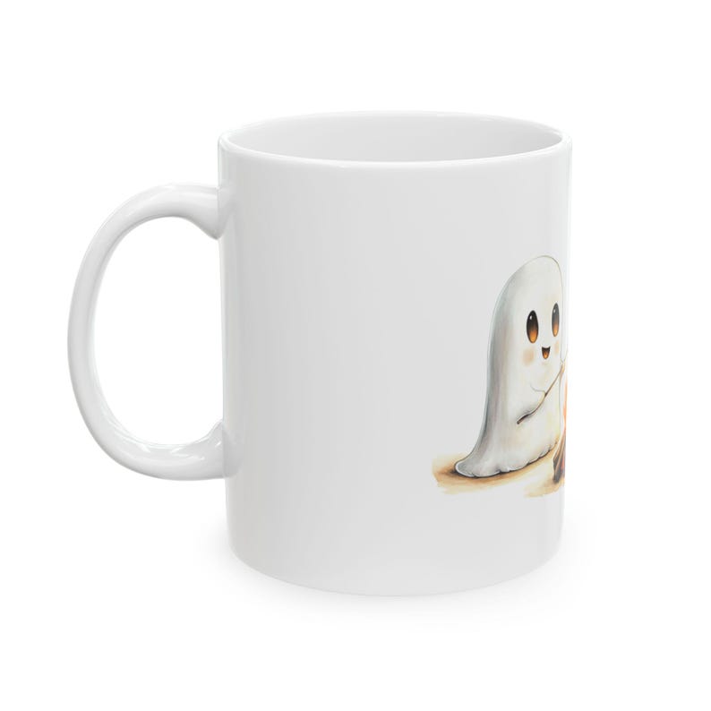 Puede incluir: Taza de cer&aacute;mica blanca con una ilustraci&oacute;n de un fantasma lindo sosteniendo un palo sobre una peque&ntilde;a fogata. El fantasma tiene una cara amigable con ojos grandes y una peque&ntilde;a sonrisa.