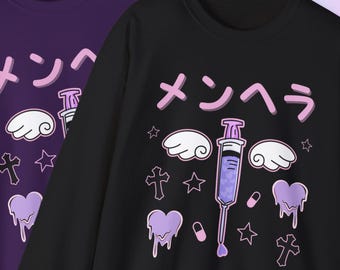 May include: Two sweatshirts, one purple and one black, featuring a kawaii design. The design includes Japanese text, a syringe, clouds, stars, hearts, and crosses in shades of purple and white.