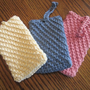 May include: Three crocheted dishcloths in yellow, blue, and pink. The dishcloths are made with a textured stitch and have a square shape.