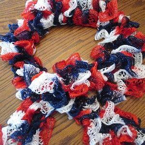 May include: A red, white, and blue crocheted scarf with a ruffled texture.