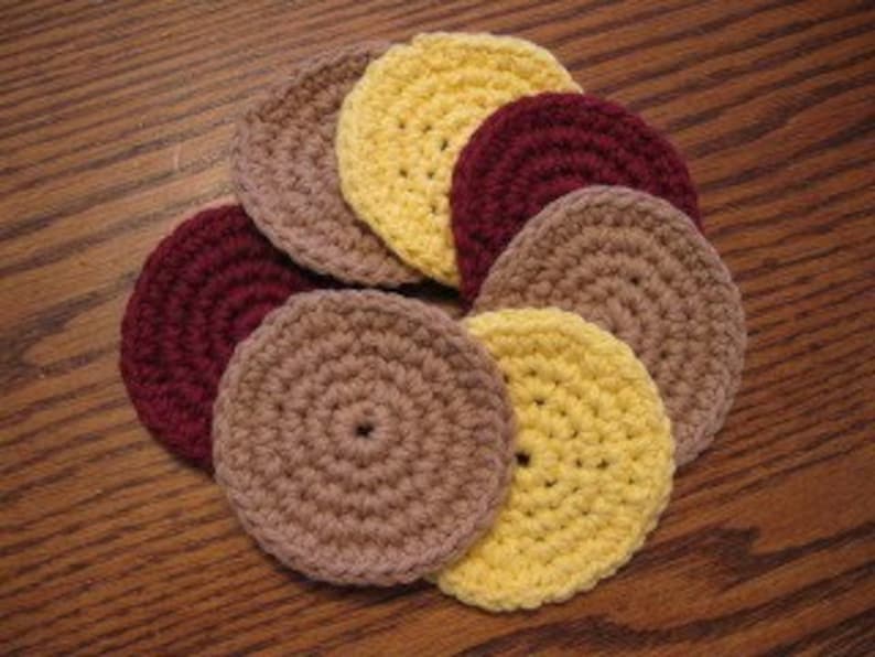 Peut inclure: Ensemble de huit dessous-de-verre en crochet de couleur jaune, marron et bordeaux. Les dessous-de-verre sont ronds et pr&eacute;sentent un design simple et textur&eacute;.