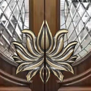 May include: A pair of ornate brass door handles in the shape of a lotus flower. The handles are mounted on a wooden door with a glass panel.