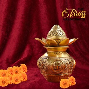 Peut inclure: Un pot en laiton dor&eacute; avec un couvercle d&eacute;coratif et des accents en forme de lotus. Le pot pr&eacute;sente des gravures complexes et un symbole sur le devant. Le fond est un tissu rouge fonc&eacute;, avec des fleurs orange au premier plan. Le logo The Brass Handicrafts est en haut &agrave; droite.