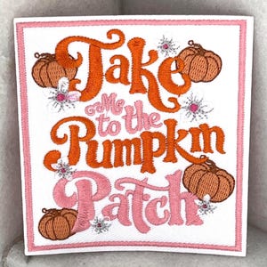 May include: Embroidered square patch with the text "Take Me to the Pumpkin Patch" in orange and pink. The design includes pumpkins and floral accents, all on a white background with a pink border.