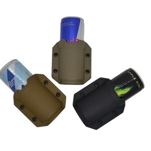 May include: Three beverage can holders in tan, brown, and black. Each holder has a rectangular shape with rounded corners and is secured with black rivets. Cans of Red Bull and other beverages are visible in the holders.