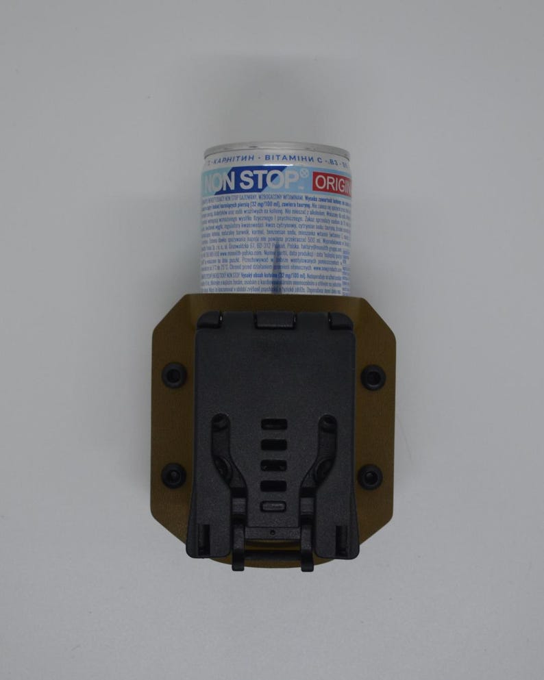 May include: A tan-colored tactical pouch with a black clip and a cylindrical container. The container has blue and white text that reads "NON STOP ORIG". The pouch is designed to hold the container securely.