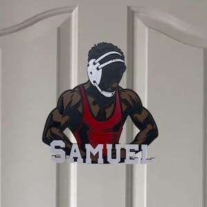 Puede incluir: Una puerta blanca con una manija de puerta dorada. Un gr&aacute;fico de luchador con el nombre "SAMUEL" est&aacute; pegado a la puerta.