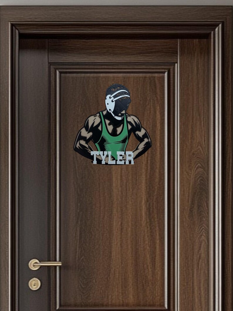 Puede incluir: Una silueta de lucha libre verde y negra con un protector de cabeza y el nombre "TYLER" impreso debajo. La silueta est&aacute; en una puerta de madera marr&oacute;n.