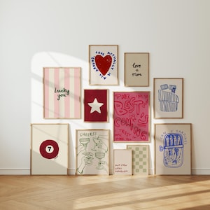 May include: A collection of framed art prints with various designs and text. The prints include a red heart, a star, a striped pattern with "Lucky you", a pool ball with the number 7, and a sardine can illustration. The color palette includes pink, red, and blue.