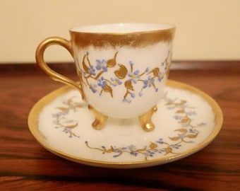 Taza y platillo de té de porcelana Limoges antigua con diseño floral en oro y blanco, circa 1890-principios de 1900.