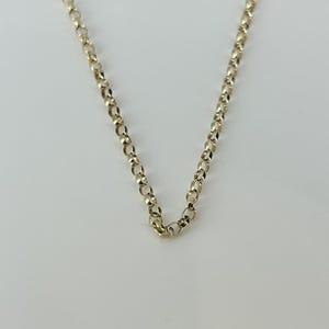 May include: A gold-toned metal chain necklace featuring a series of uniform, circular, interlocking links. The chain is arranged in a V-shape, showcasing the consistent round design of each individual link throughout the entire length of the piece.