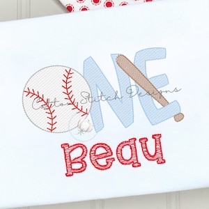 May include: A white shirt featuring an embroidered design with a baseball, a light blue letter O, and a brown baseball bat forming the letter N. The word ONE is stitched in light blue, and the name Beau is embroidered below in red.