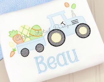 May include: White fabric with a light blue tractor design carrying Easter eggs and carrots. The tractor has black wheels and the name "Beau" embroidered in light blue. The design includes orange, green, and yellow accents.