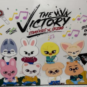 May include: A white background features cartoon character illustrations of SKZOO, the Stray Kids characters, with musical notes and text. The text includes "The Victory" and "SKZOO everywhere all around the world."