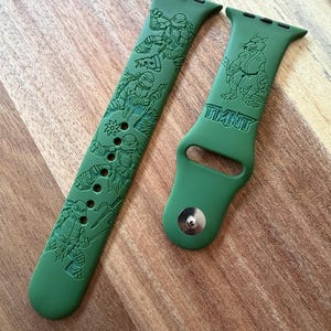 Può includere: Cinturino verde per orologio con incisioni dei personaggi delle Tartarughe Ninja. Il cinturino presenta la scritta "TMNT" e illustrazioni dei personaggi in pose dinamiche. Realizzato in materiale flessibile, per smartwatch.