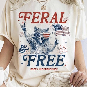 Unleash Your Inner Trash Panda for the 250th Anniversary! 🇺🇸🦝🎆 Celebrate the big 2-5-0 with a side of unhinged humor! Our "Feral & Free" raccoon tee is the ultimate party shirt for America’s 250th Independence Anniversary in 2026. If you’re more about "rocking out" at the BBQ than being perfectly poised, this "trash panda" is your spirit animal.