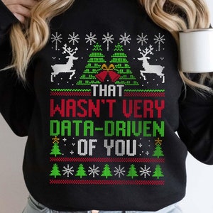 May include: Black Christmas sweater with a green and red pixelated design featuring reindeer, Christmas trees, and the text "That wasn't very data-driven of you."