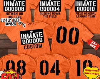 May include: A collection of orange t-shirts featuring black graphic prints. The front designs display the text INMATE followed by a number and a pumpkin icon. Some shirts include additional text like HITMAN ON THE LINE. The backs feature large black numbers.