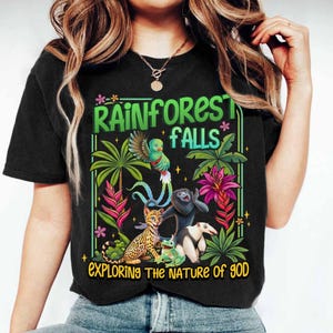 May include: Black t-shirt with a colorful rainforest graphic. The design includes a parrot, lemur, ocelot, frog, and anteater, with the text "Rainforest Falls" and "Exploring the Nature of God."