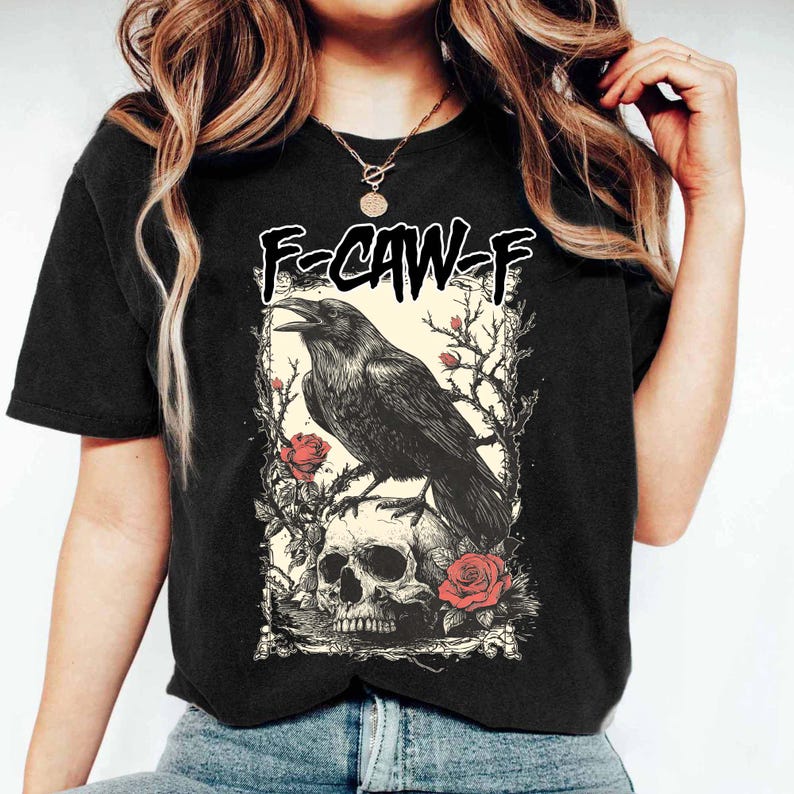 Puede incluir: Camiseta negra con un gr&aacute;fico detallado de un cuervo posado sobre una calavera, rodeado de rosas y ramas. El texto "F-CAW-F" est&aacute; encima del cuervo. El dise&ntilde;o tiene una est&eacute;tica g&oacute;tica o alternativa.