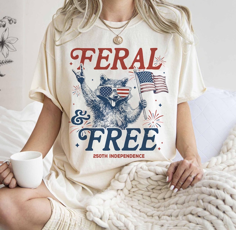 Unleash Your Inner Trash Panda for the 250th Anniversary! 🇺🇸🦝🎆 Celebrate the big 2-5-0 with a side of unhinged humor! Our "Feral & Free" raccoon tee is the ultimate party shirt for America’s 250th Independence Anniversary in 2026. If you’re more about "rocking out" at the BBQ than being perfectly poised, this "trash panda" is your spirit animal.