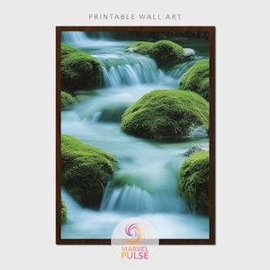 May include: Printable wall art featuring a serene waterfall scene. The image showcases flowing water cascading over moss-covered rocks, creating a tranquil and natural landscape. The artwork is framed in a dark brown border, with the text "PRINTABLE WALL ART" at the top.