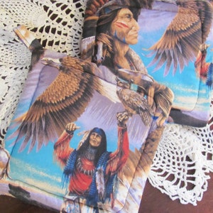 May include: Two quilted pot holders with a Native American theme. The pot holders feature images of Native American men with eagles and a blue, purple, and brown color scheme.