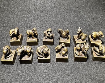 May include: A set of twelve bronze animal figurines, each on a small square base. The animals depicted are a horse, ram, monkey, rooster, dog, pig, rat, ox, tiger, rabbit, dragon, and snake. The figurines are arranged in two rows.