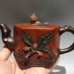 以下が含まれることがあります： 六角形のボディ、枝のような取っ手と注ぎ口を備えた茶色のセラミックティーポット。 ティーポットは、彫刻されたオークの葉とドングリで装飾されています。 蓋には小さな装飾ノブが付いています。 ティー愛好家向けのユニークな作品。