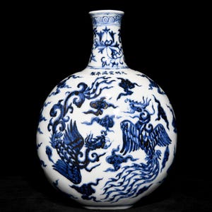 Op de afbeelding: Een witte porseleinen vaas met een rond lichaam en een smalle hals. De vaas is versierd met een blauw en wit ontwerp van een feniks en wolken. De vaas heeft een Chinese inscriptie op de hals.