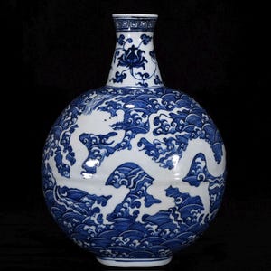 Op de afbeelding: Een blauw-witte keramische vaas met een bolvormige body en een smalle hals. De vaas heeft een gedetailleerd ontwerp van een draak te midden van wervelende golven. De hals is versierd met een geometrisch patroon en bloemmotieven.