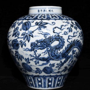 May include: A large, blue and white ceramic vase with a detailed dragon and floral design. The vase features a wide body, a narrow neck, and a decorative rim. The dragon is depicted in a dynamic pose, and the vase has Chinese characters.