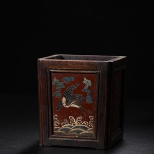 May include: A rectangular dark brown wooden brush pot featuring a central inset panel with a red background. The panel displays a detailed depiction of a crane in flight above stylized waves, accented with blue clouds and gold-toned detailing.