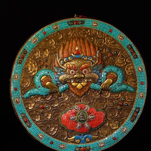May include: A circular decorative wall hanging featuring a central dragon design. The dragon is gold, red, and blue, with turquoise detailing. The border is turquoise, and the background is bronze. The piece has an intricate, textured design.