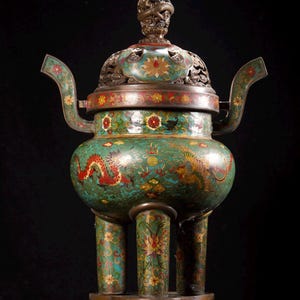 Op de afbeelding: Een sierlijke, antieke wierookbrander met een gedetailleerd drakenontwerp. Het vat is voornamelijk blauwgroen met rode, gele en witte bloemaccenten. Het heeft een deksel met een drakenkroon en drie decoratieve poten.