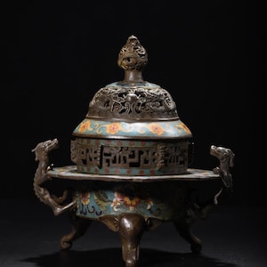 Op de afbeelding: Een antieke bronzen wierookbrander met een deksel, met ingewikkelde draken- en bloemmotieven. De brander heeft een turquoise en gele emaille afwerking, met draakvormige handvatten en poten. Het deksel is bekroond met een decoratieve bekroning.