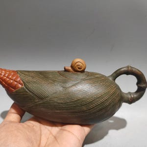 Peut inclure: Théière artisanale unique en forme d'épi de maïs. La théière est principalement vert olive avec une pointe de maïs brun rougeâtre et une petite poignée de couvercle en forme d'escargot. La poignée est de style bambou.
