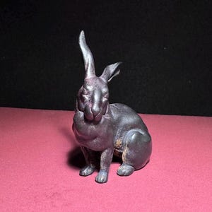 May include: A black ceramic rabbit figurine with a glossy finish. The rabbit is sitting with its ears upright and its head tilted slightly to the side.