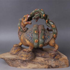 Può includere: Una scultura in legno intagliata a mano che rappresenta un drago e un serpente intrecciati. Il drago è dorato, verde e blu, mentre il serpente è verde e giallo. La scultura è montata su una base in legno.