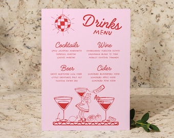Puede incluir: Tarjeta de menú rosa con un gráfico de bola de discoteca roja y texto rojo que enumera las bebidas para una boda. El texto incluye cócteles, cerveza, vino y sidra. La tarjeta también presenta una ilustración de dibujos animados de una novia sosteniendo tres copas de martini.