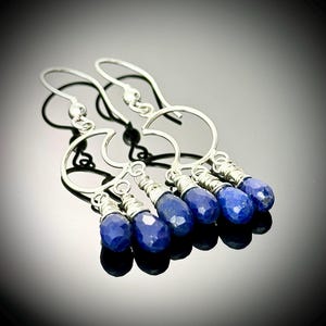 May include: A pair of silver crescent moon earrings with dangling blue lapis lazuli gemstone drops.
