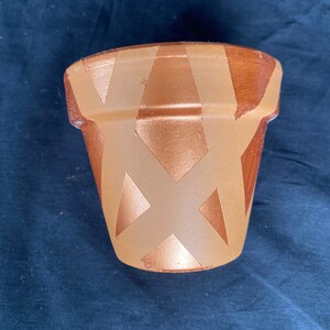 May include: A terracotta flower pot with a geometric pattern painted in gold and brown.