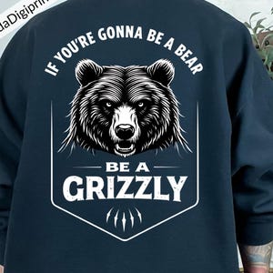 May include: Navy blue sweatshirt featuring a detailed black and white illustration of a grizzly bear's head. The text "IF YOU'RE GONNA BE A BEAR BE A GRIZZLY" is printed above and below the bear graphic. The design includes bear claw marks.