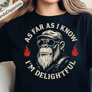 Puede incluir: Camiseta negra con un diseño de gorila con gafas de sol y gorra, con el texto "AS FAR AS I KNOW I'M DELIGHTFUL" en un círculo. Llamas rojas a ambos lados del gorila. El logotipo de PandaDigiprints está en la esquina superior izquierda.