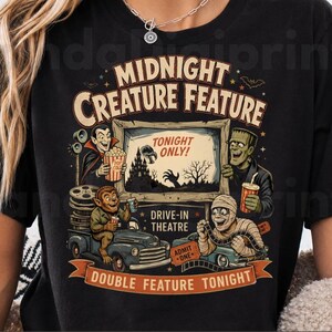 Peut inclure: Un t-shirt noir avec une impression graphique portant le texte MIDNIGHT CREATURE FEATURE, TONIGHT ONLY, DRIVE-IN THEATRE, ADMIT ONE et DOUBLE FEATURE TONIGHT. Le motif représente un vampire, le monstre de Frankenstein, un loup-garou et une momie.