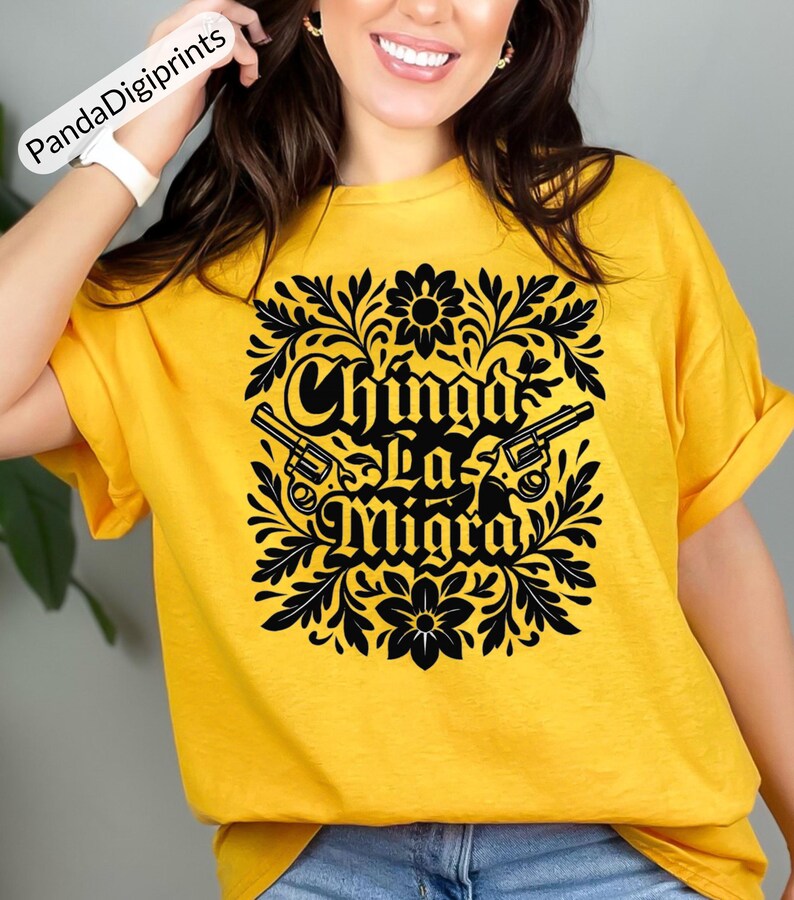 May include: A yellow t-shirt featuring a black floral design with the text "Chinga La Migra" and two guns. The shirt is made of a soft material and has short sleeves.